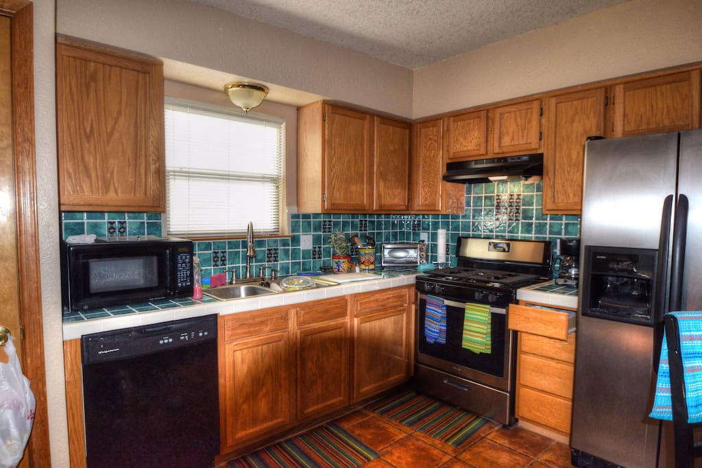 Kitchen with side by side fridge, dishwasher, microwave and seating for four.