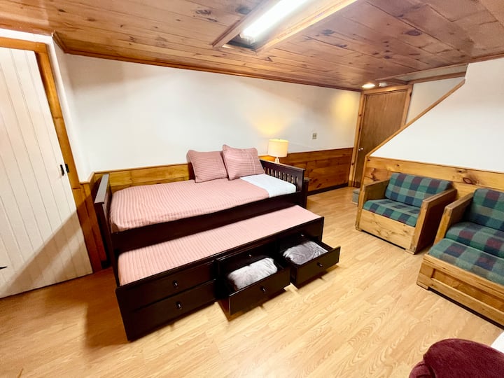Trundle bed in basement with extra blankets and seating area