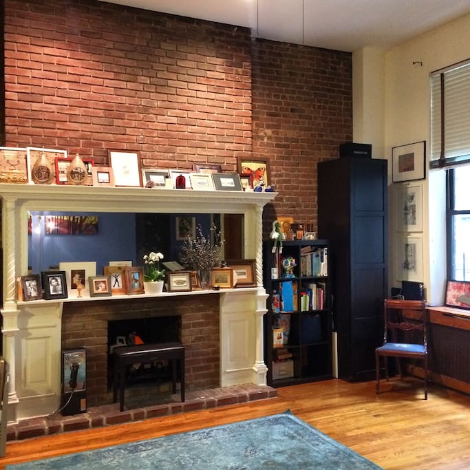 living room with queens sofa bed, mirror and 1910 brick wall with a fire place, small manhattan inner garden view:)