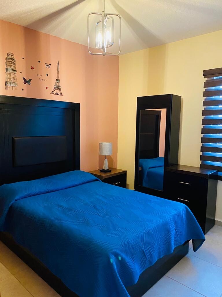 Schlafzimmer 3 verfügt über einen Kleiderschrank, einen Euro, eine Kommode und einen Spiegel sowie ein Fenster mit Blick auf den Garten. 