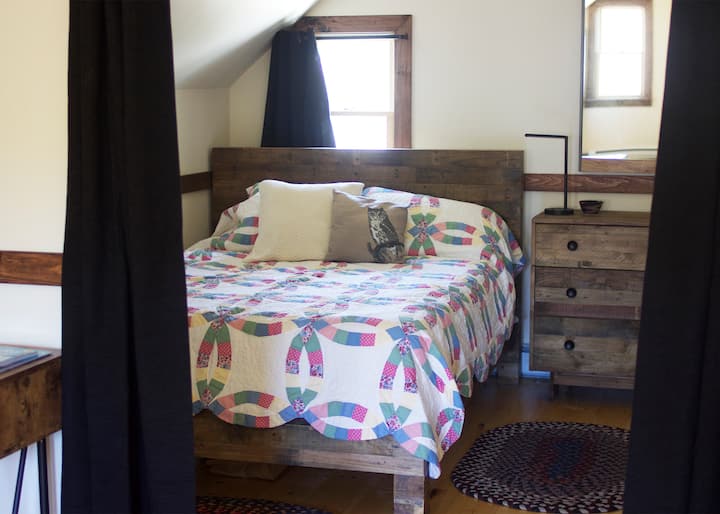 Looking into the charming bedroom from the main living space (a closeable dark curtain separates the space).