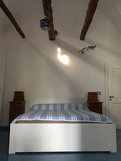 Camera da letto con travi a vista, guardaroba a sei ante, comodini deco’ e cassettone napoletano