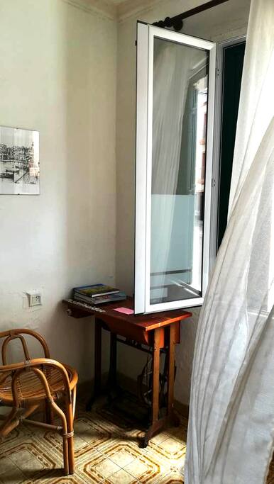 Una mesa,silla y el ventanal con cortina