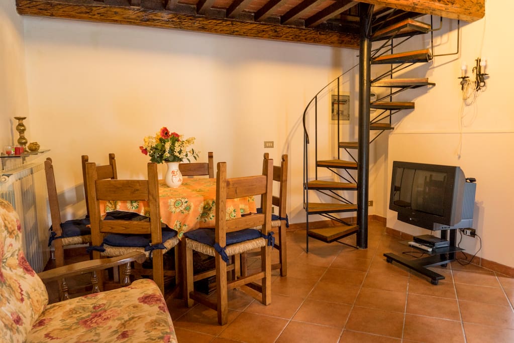 ingresso-sala con TV, divano, tavolo con sedie e caminetto