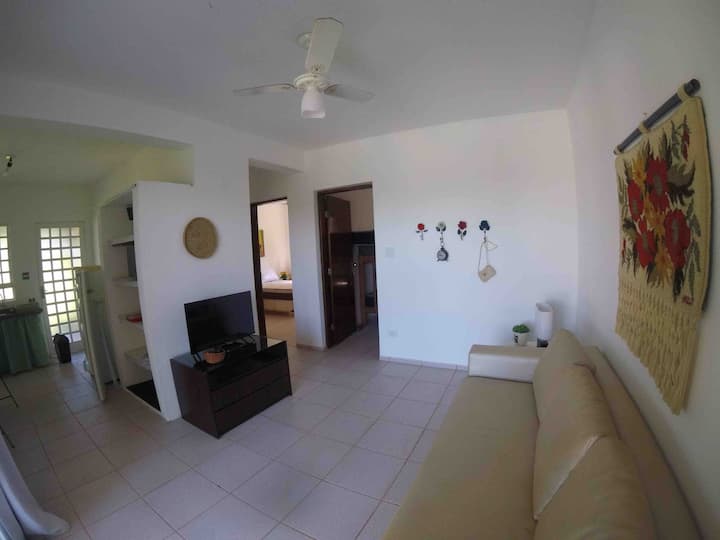 03号公寓 客厅、厨房和两间卧室的概览，客厅配备智能电视、单人沙发床和天花板风扇 