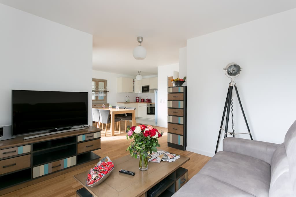 First level, living room with sofa, tv, and dining room and kitchen.
Au premier niveau, le salon avec le canapé, la télé, la salle à manger, la table, la cuisine.