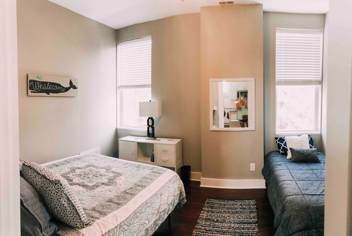 Queen sized bed and a twin bed; ceiling fan overhead. 