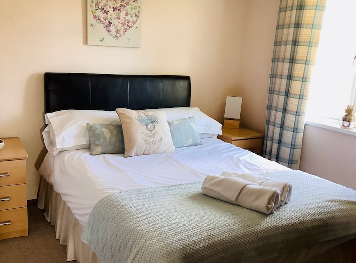 غرفة نوم مزدوجة مع خزانة ملابس وطاولات بجانب السرير وتلفزيون وحمام داخلي صغير