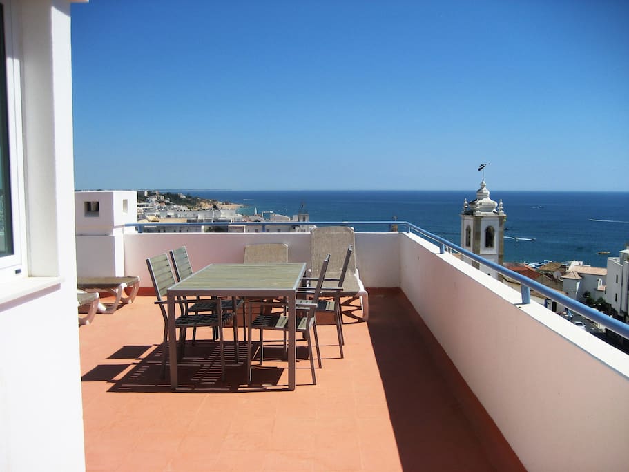 Terrace with sea view, sun beds, table, and shade