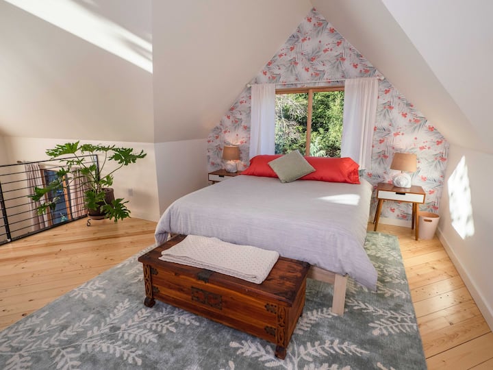 Palm fronds and flowers are the backdrop to a queen-sized bed in the upstairs sleeping alcove. 