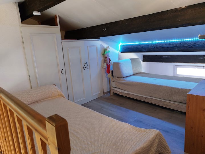 На мецанина спалнята е над всекидневната, а не затворена. Две легла за един човек. Малко пространство, но идеално за спане.
На пода има плаващ паркет. 
Малък скрин и гардероб позволяват съхранение. 