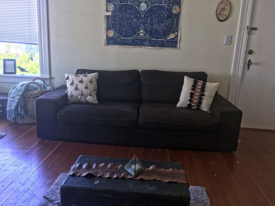 The living room has a couch and desk with plenty of room for an air mattress.