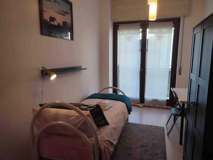 petite chambre avec lit simple, bureau avec chaise, armoire, donnant sur le balcon