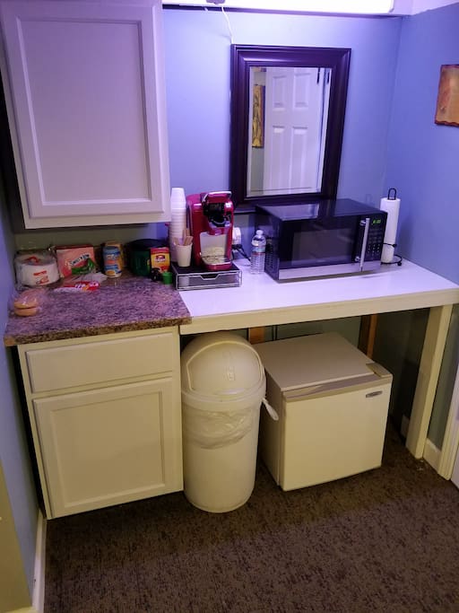 Breakfast area with fridge, microwave, Keurig and various other breakfast items.