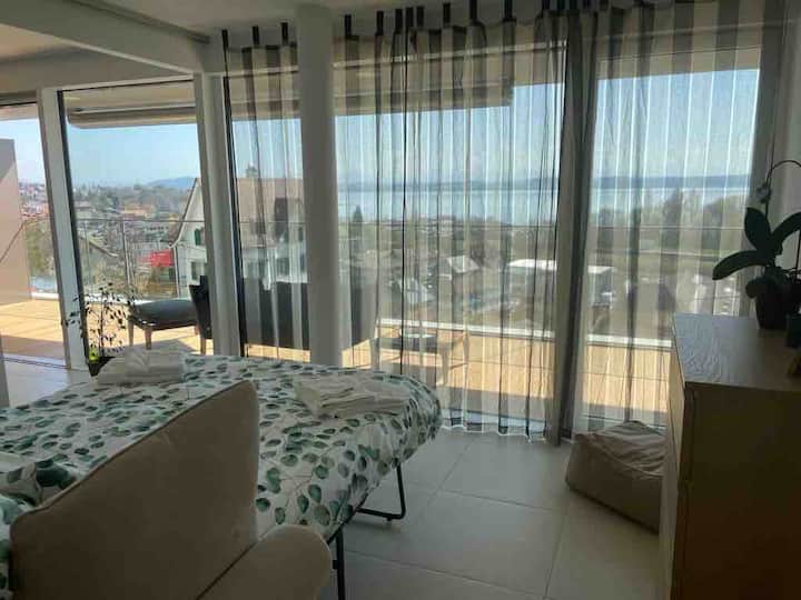 Small bedroom (12 m2) with sliding door open to the living room and couch prepared as bed (140 cm) with balcony view
