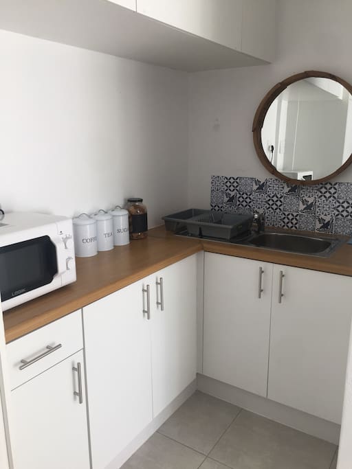 Kitchenette with microwave, a hotplate, mini fridge, coffee & tea and a small sink to wash dishes.