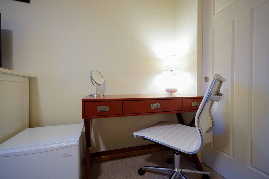 Desk with three drawers, modern chair, and vanity mirror