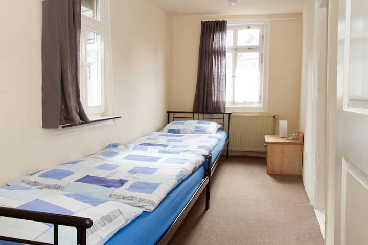 Langes Schlafzimmer mit zwei Single Betten. Dieser Raum ist sowohl vom großen Schlafzimmer als auch vom Bad zu betreten.