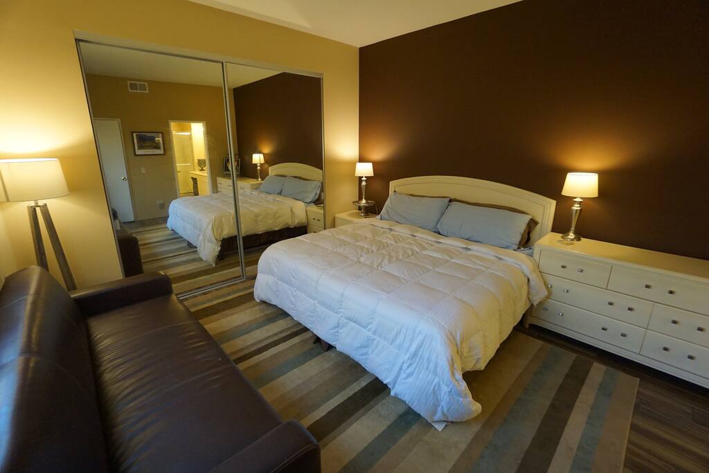 Large guest bedroom with King-size bed, folding couch, and plenty of closet space and drawers.