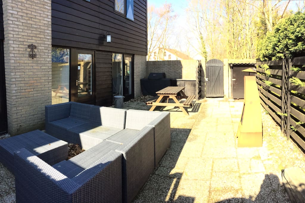 De patio vol privacy, met gezellige haard, loungeset, tuinverwarming en gas BBQ.