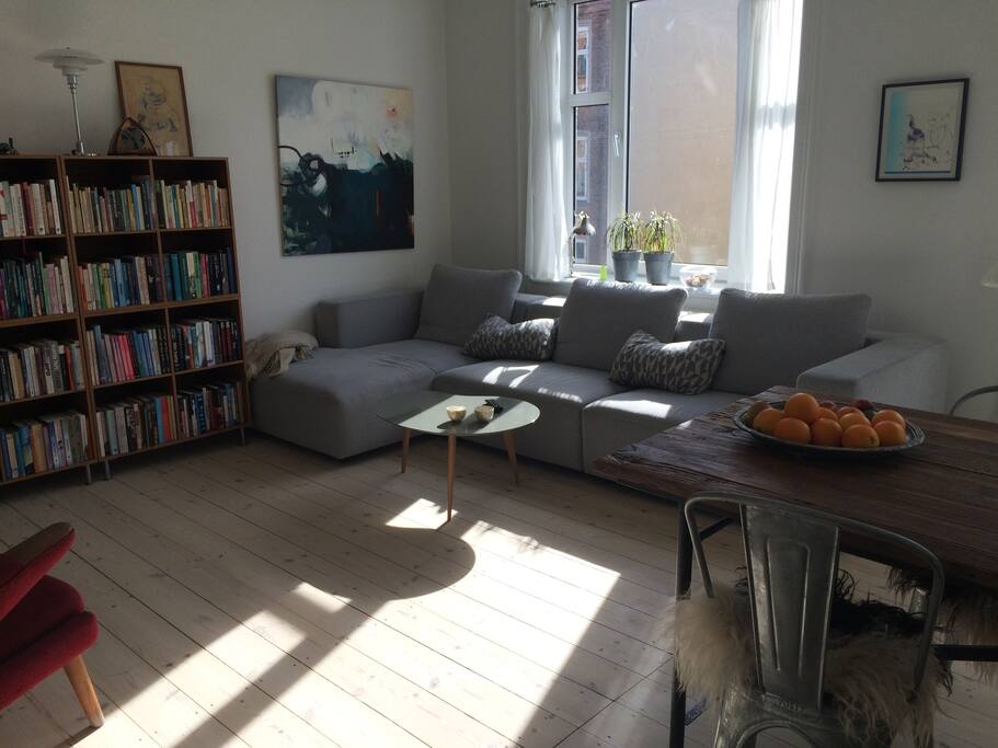 Stor lys stue med pejs, tv, sofa og spisebord