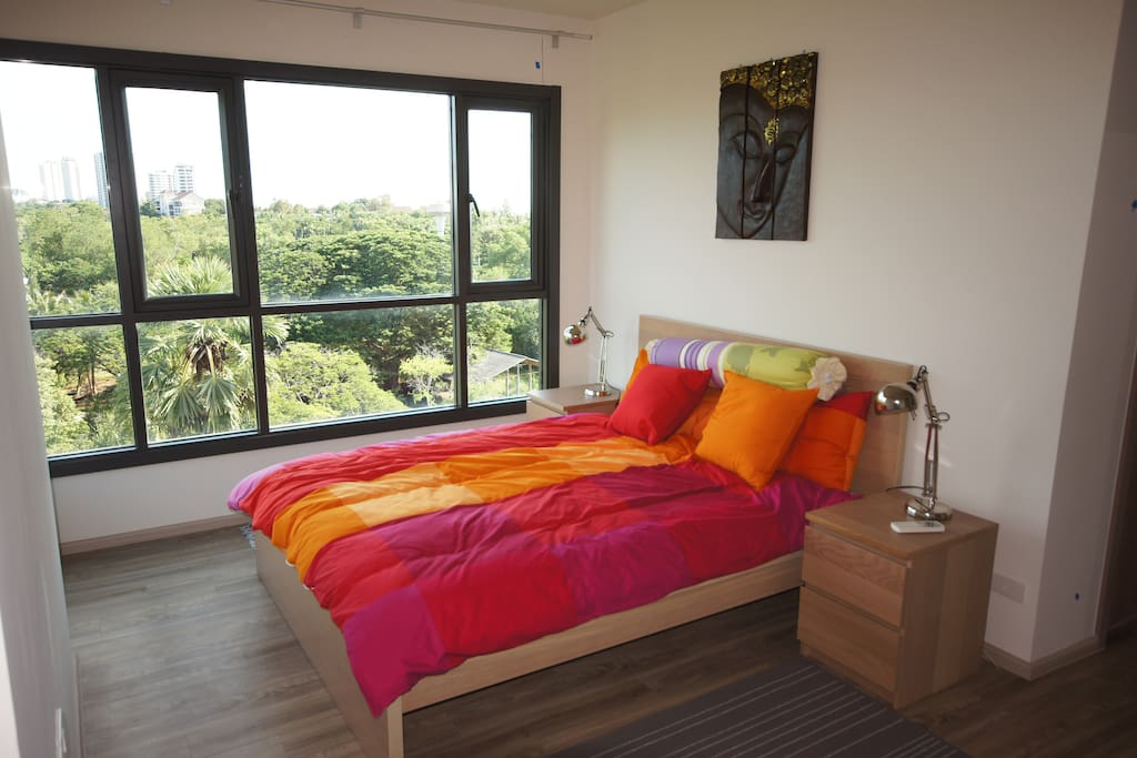 A comfy queen sized bed in a master bedroom with garden view.