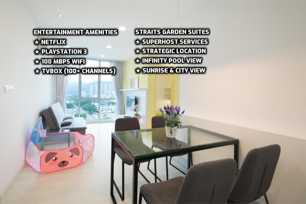 A modern living area features a glass dining table paired with black chairs. Large windows frame a city view, allowing natural light to fill the space. A corner entertainment area includes a cozy setup for Netflix and gaming, complemented by decorative accents.