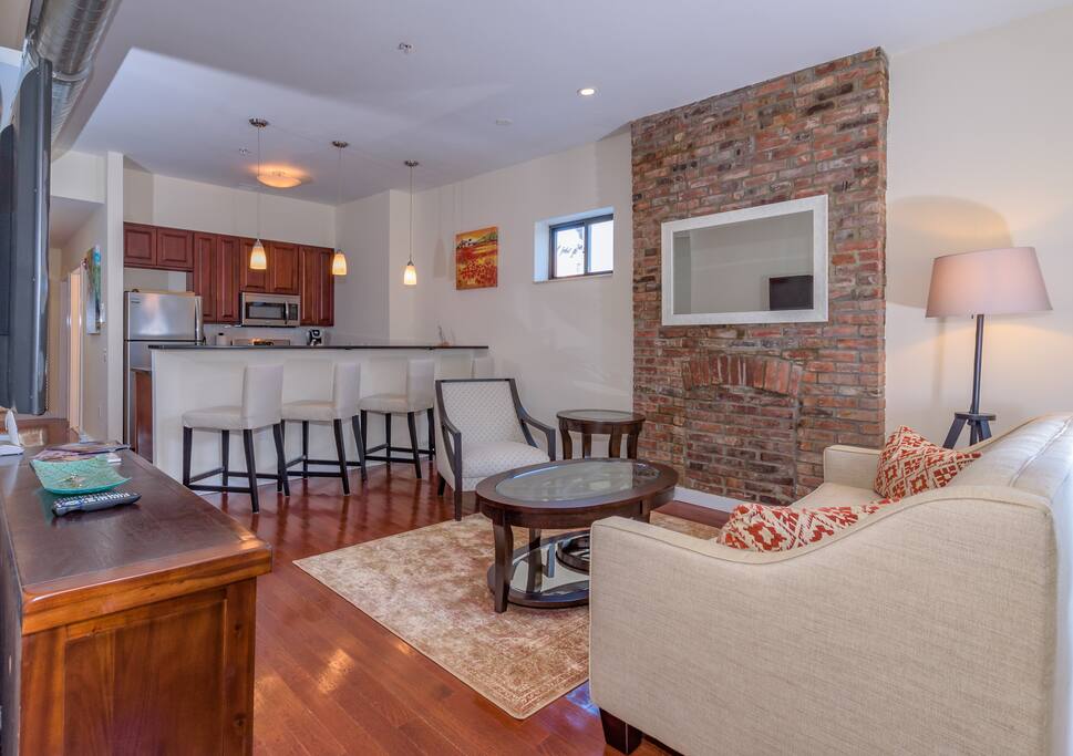 The apartment’s stylish Mid-century décor includes pops of orange, gleaming hardwood floors and exposed brick, a remnant of the building’s 1887 architectural bones.