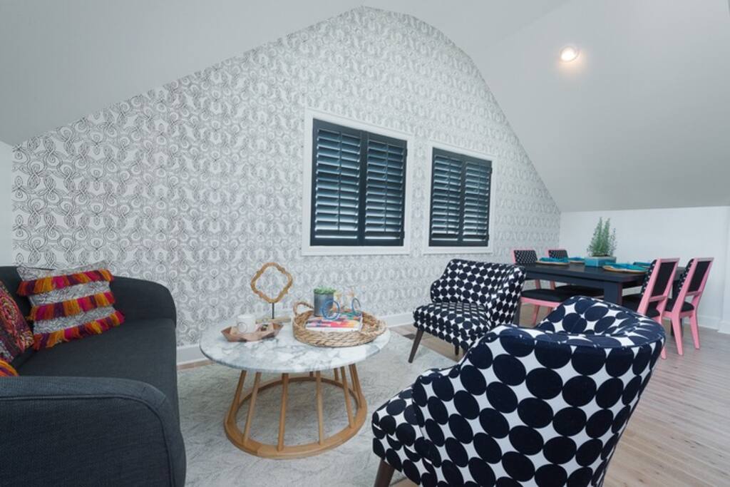 Welcome home! An open kitchen/dining area awaits. Whimsical wallpaper, cozy seating and masterful craftsmanship make this AirBnB space stellar!
