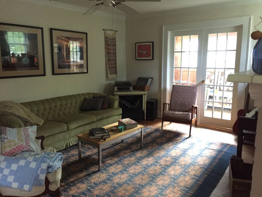 Living room with sofa, chairs, piano and fireplace.