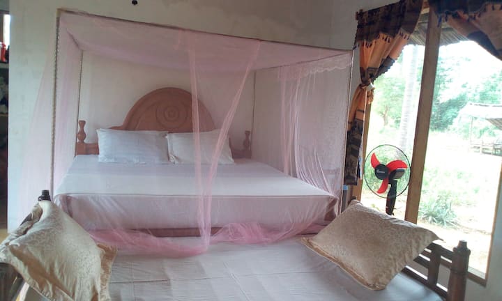 bed room with en suited bathroom running clean water, fan and mosquito net with enough space and sea view