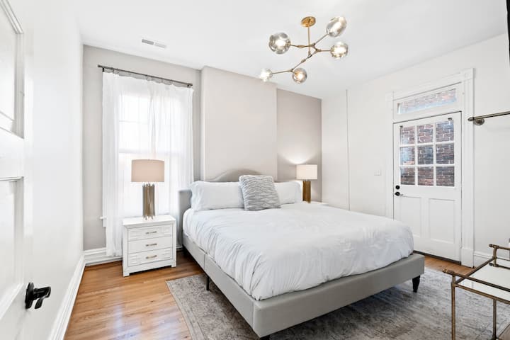 Amplio dormitorio tamaño king amplio lleno de luz con TV montada en la pared de 55 pulgadas con acceso a la zona de estar al aire libre.