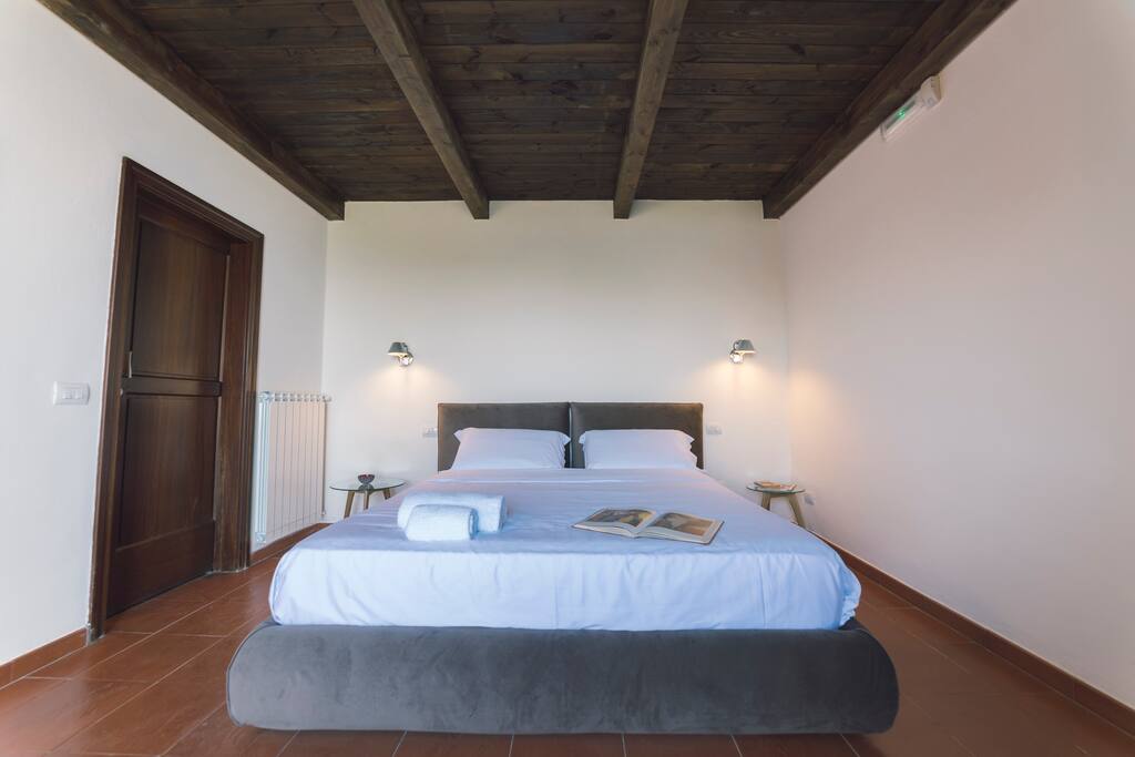 Camera elegante vista mare, dotata di letto matrimoniale king-size, con possibilità di letto aggiunto. Pavimento in cotto. Dettaglio travi a vista. Accesso diretto al giardino con ingresso indipendente.