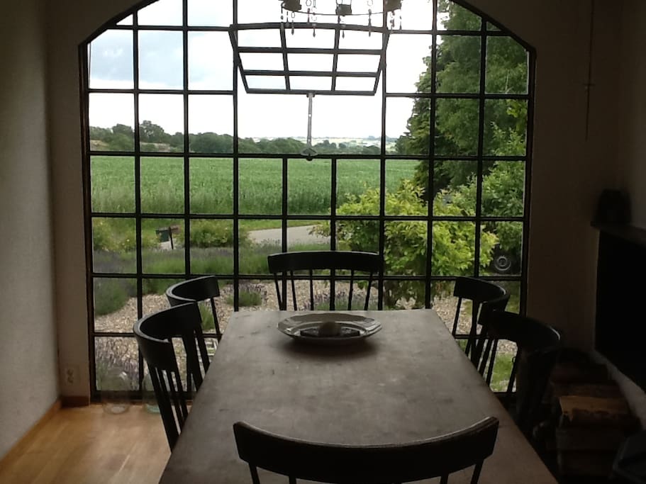 Living room (in spring, summer and autumn) with lovely view over the landscape, open fireplace, couch and dinner table.
