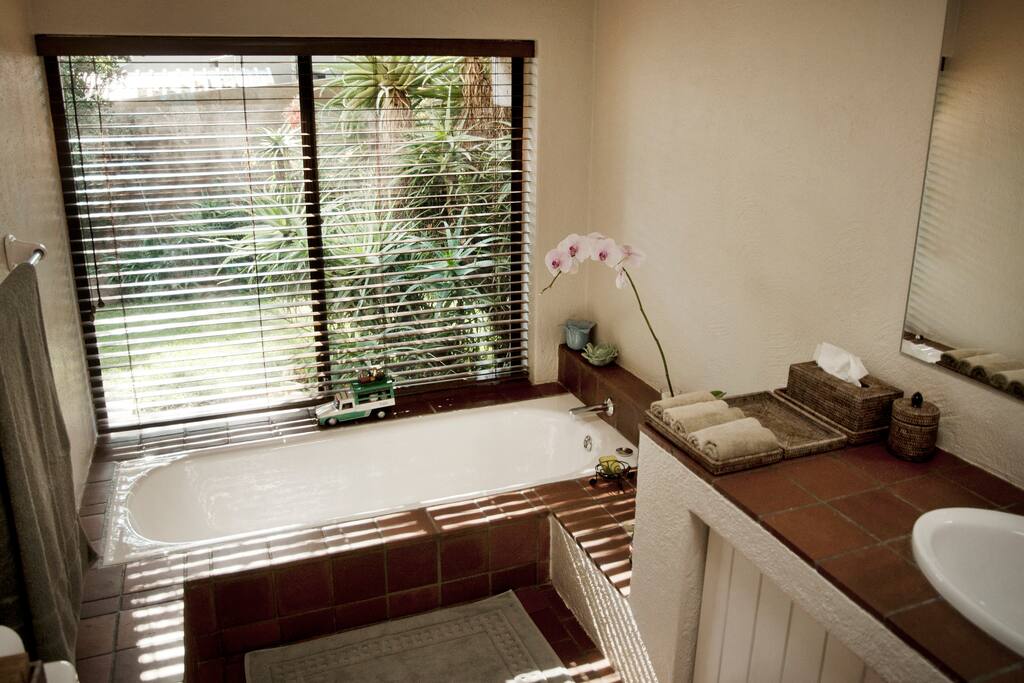 Sunken bath with hand shower overlooking the garden.