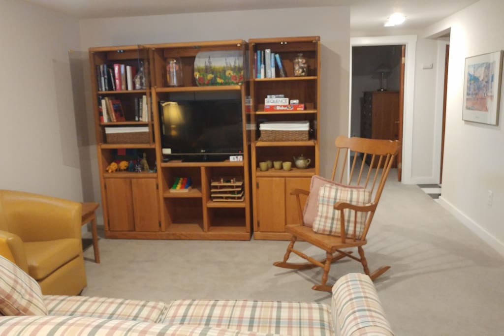 View from the dining area shows entertainment center. The TV is equipped with a Chromecast device that allows you to cast accounts you have available on your phone, e.g. Netflix, Hulu, and Spotify, to the TV for streaming. The hall to the bedroom and bathroom are on the right.