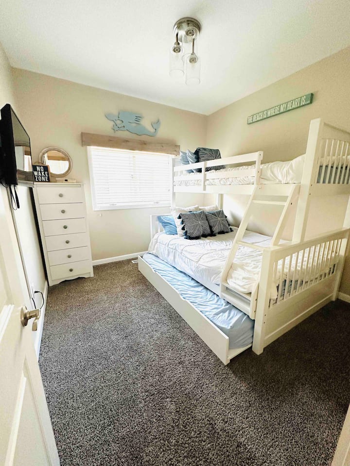 Etagenbett mit zwei Einzelbetten über Doppelbett und Kommode. TV mit Roku. 