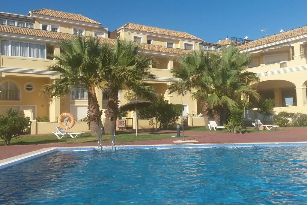Fachada interior de pequeña urbanización con piscina y padel gratis