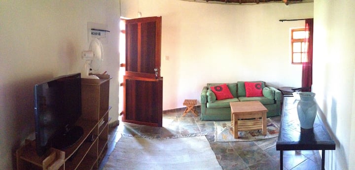  Dnevni boravak s kaučem na razvlačenje i kupaonicom s tušem.  Vrata L vode do vrta i glavne kuće 