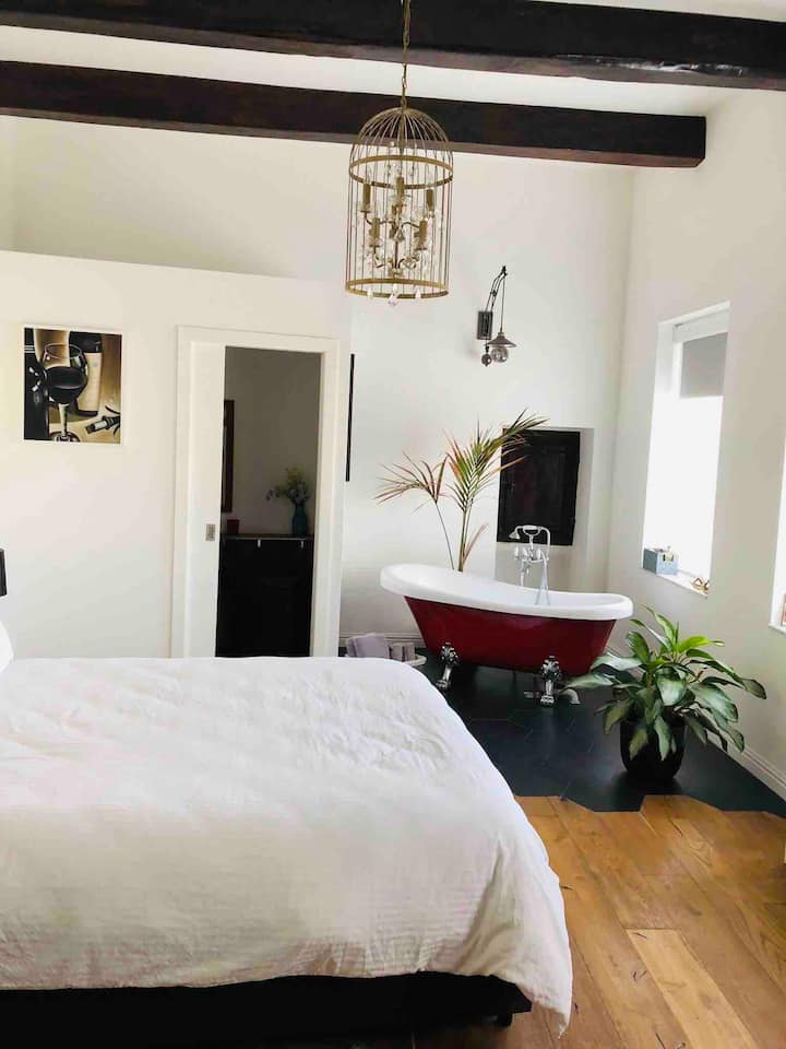 红色卧室设有独立浴室、带有漂亮的法式窗户的独立卫生间、一张舒适的加大双人床和一个漂亮的室外露台。我最喜欢的房间有原木门和裸露的横梁