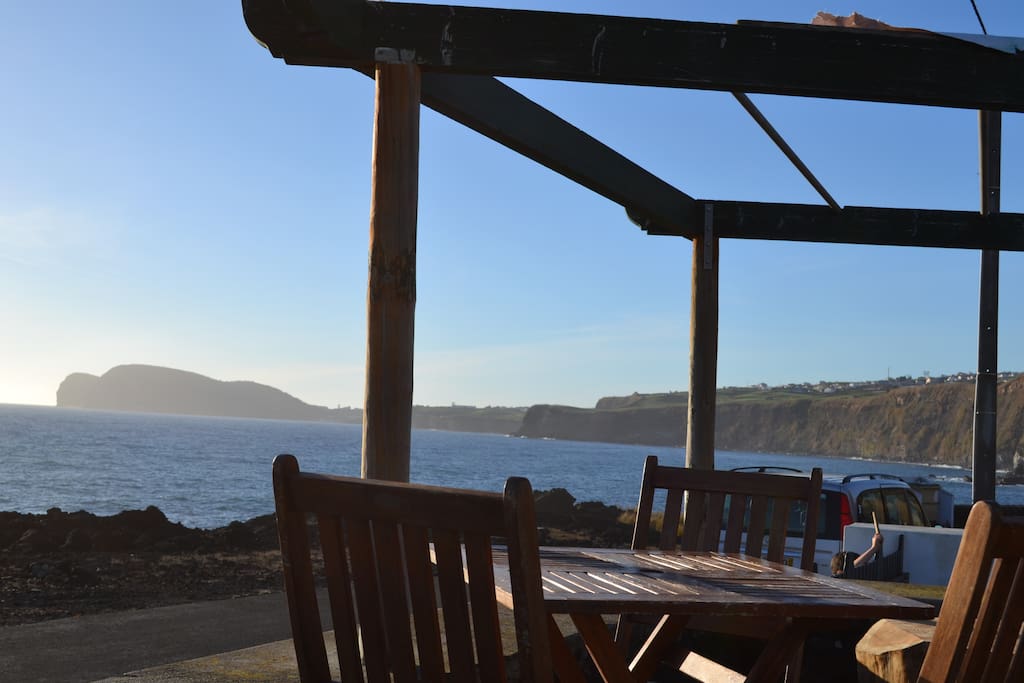 Terraço mesa e cadeiras com vista retalhada da costa, Baía de Angra e Monte Brasil
