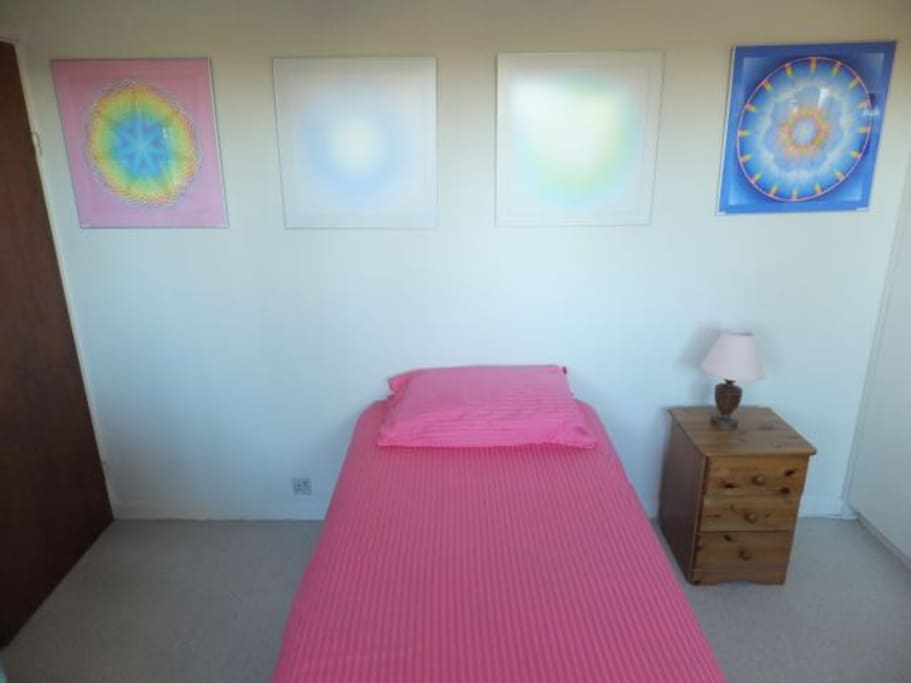 Single bed with mandalas above it in downstairs bedroom.