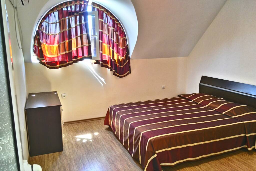 Spacious bedroom with queen size bed and air conditioner. A lot of natural light coming in.