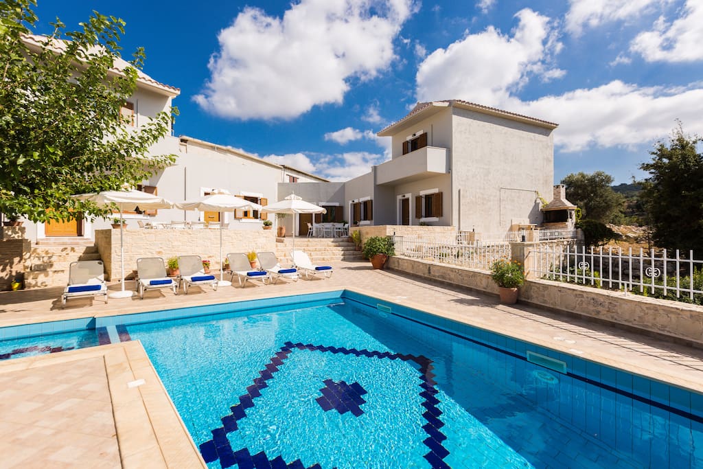 Overview of the villa and pool area with sun beds, umbrellas and sitting areas