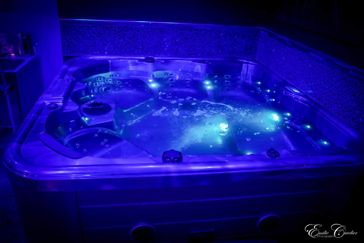 A luxurious jacuzzi is shown, featuring soft blue lighting and jets creating soothing bubbles. The design includes a spacious interior, allowing for relaxation and comfort, with tiled walls reflecting the ambient glow.