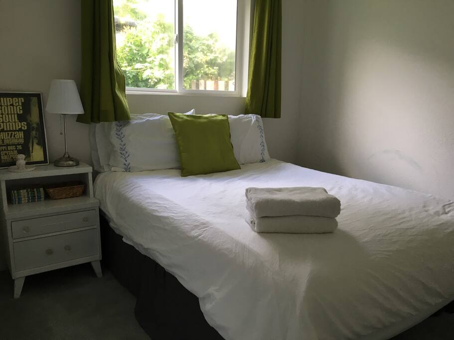 Bedroom #2 with bright, green curtains and local art