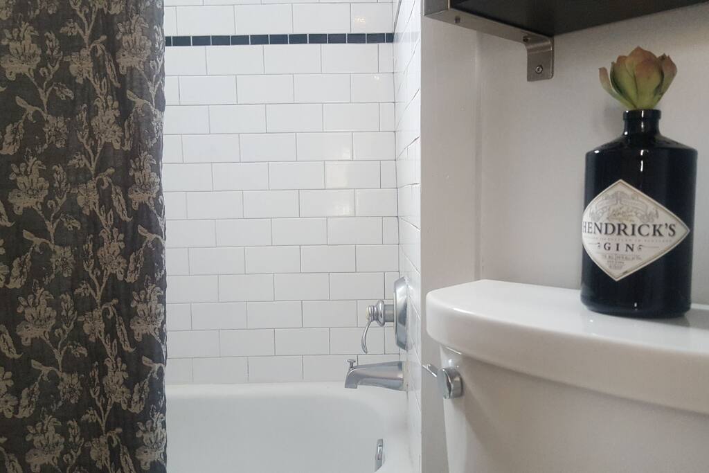The bathroom has a full bath tub with shower.