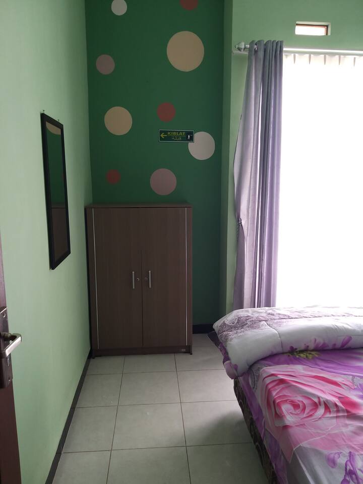 Kamar pertama dengan dekorasi dinding warna hijau sejuk dengan ornamen polkadot, fasilitas kamar ini lemari, kaca rias, lampu tidur dan tempat tidur spring bed ukuran king size (180x200) yang nyaman.