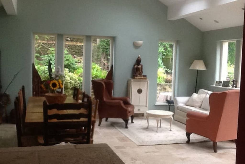 The bright and airy garden room with dining table and comfy sitting area.