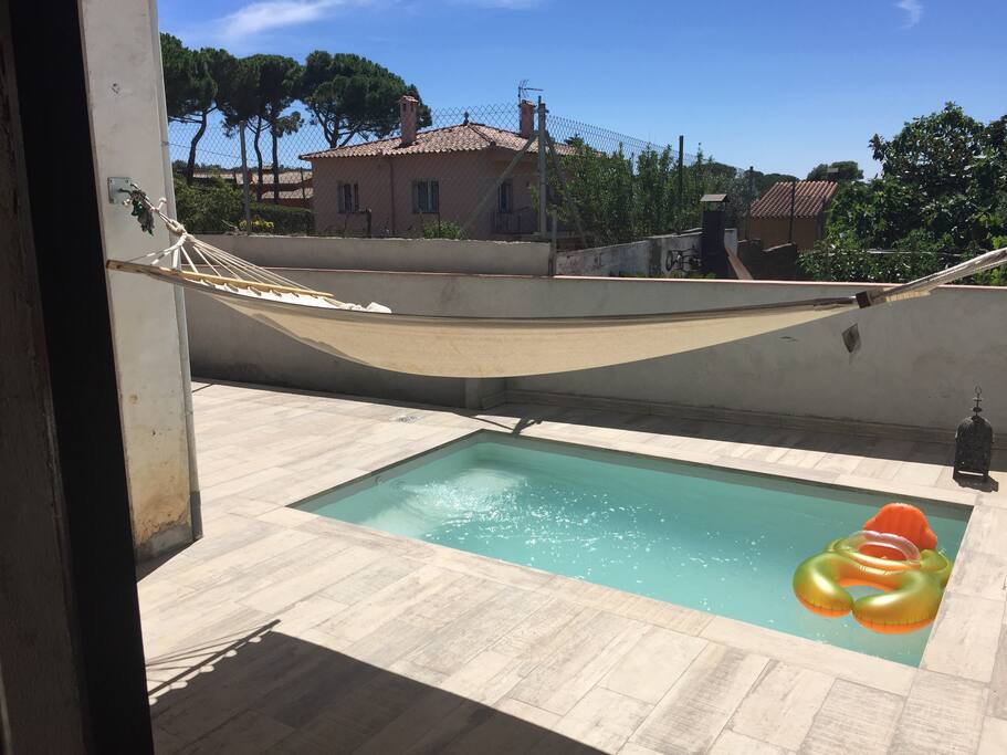 Piscina, patio con amaca, mesa y sillas.